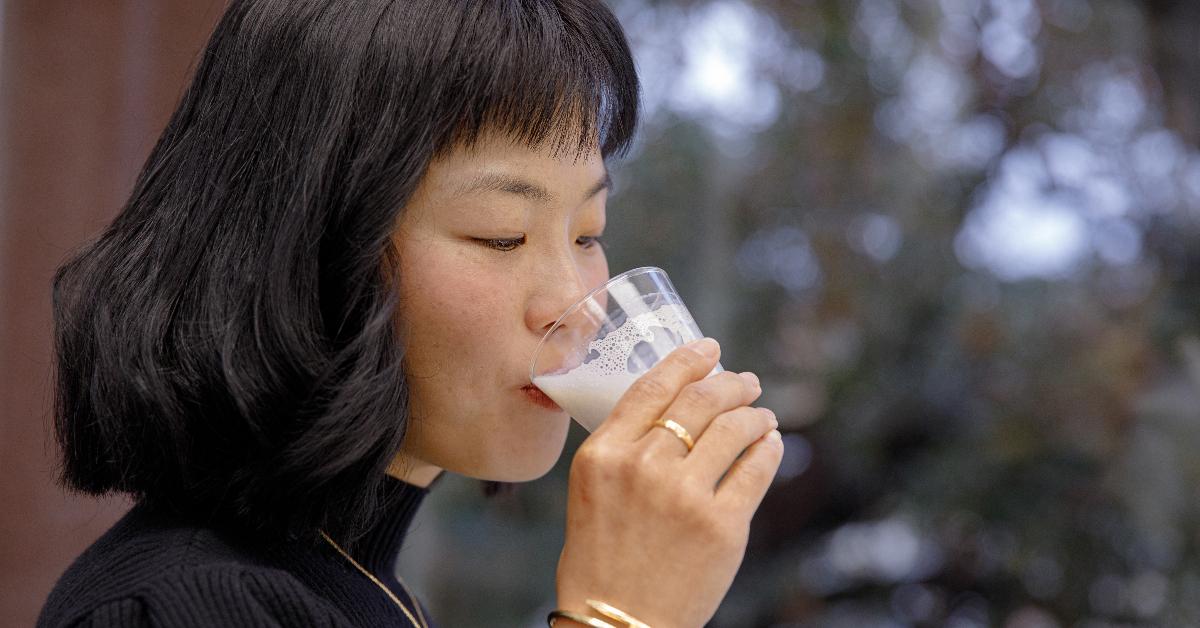 Photo of TurtleTree CEO and co-founder Fengru Lin drinking a glass of plant-based milk with vegan lactoferrin