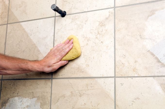 person cleaning shower tile with a sponge