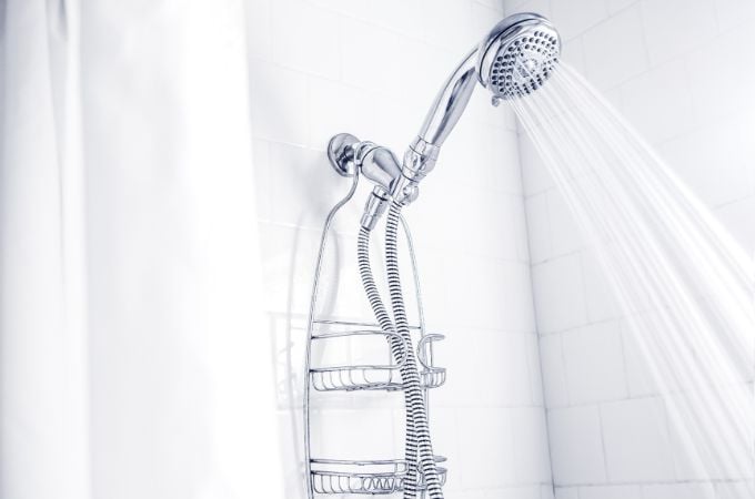 shower spraying water in shower with white tile